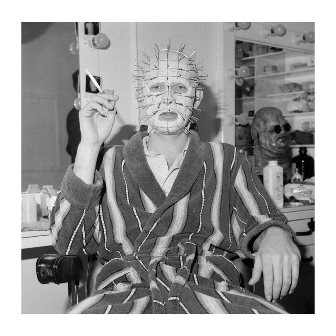 Black and white portrait of actor Doug Bradley seated in his dressing gown smoking a cigarette behind the scenes on Hellbound Hellraiser 2 set. Classic horror film from Clive Barker 1988 - Ground breaking makeup and effects Geoff Portas legendary Make-Up artist . Cast includes Doug Bradley, Simon Bamford, Barbie Wilde  and Nicholas Vince. 