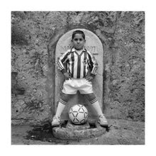 Black and white portrait of a young boy in Real Betis Balompie football kit, standing in front of a fountain. Pollensa,  Majorca 1992.